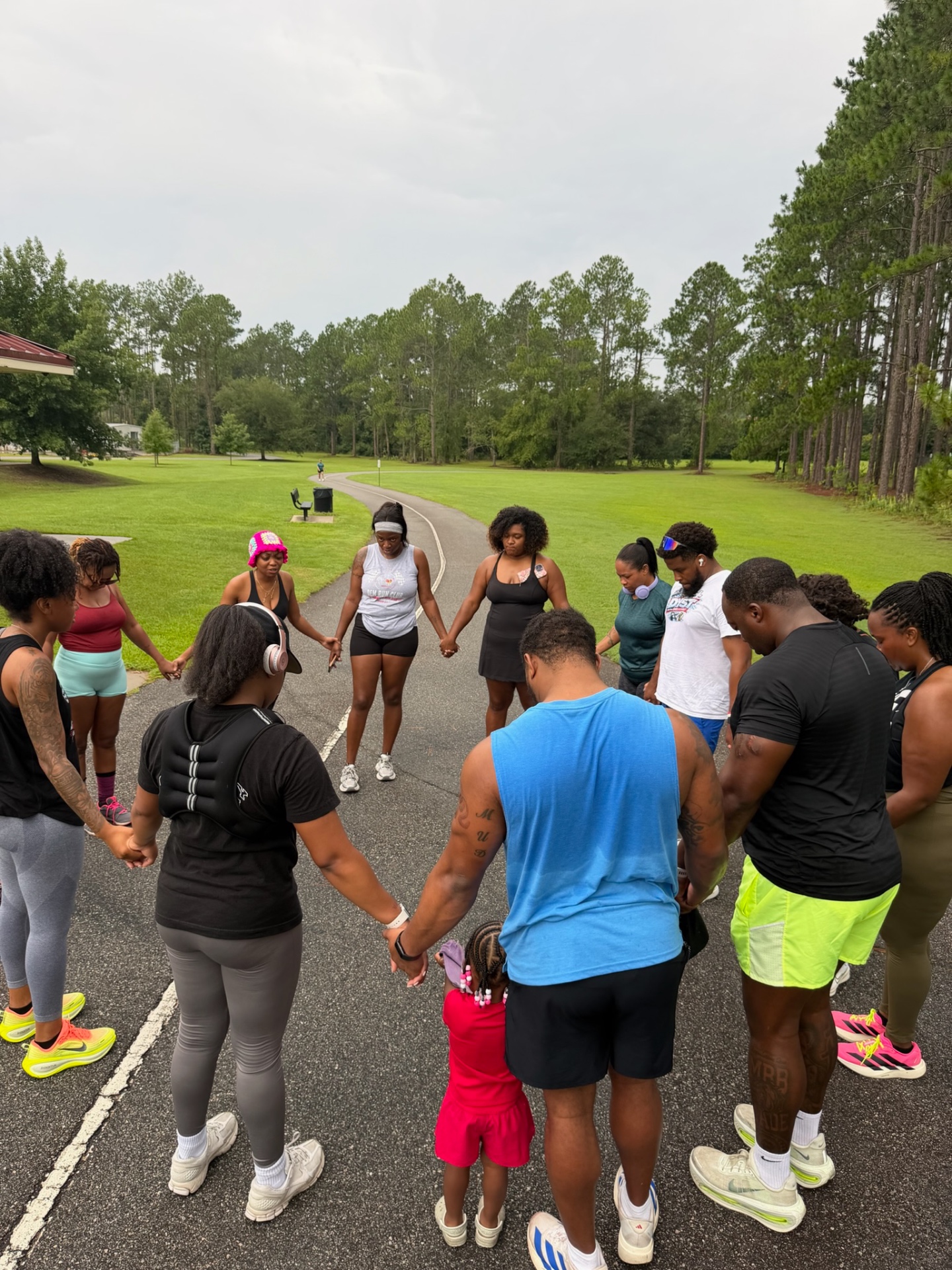 D.E.M Run Club members holding hands in a prayer circle before a run